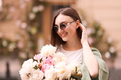 Photo of Charming woman with bouquet of beautiful peonies on city street