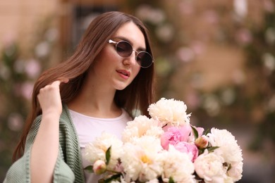 Photo of Charming woman with bouquet of beautiful peonies on city street