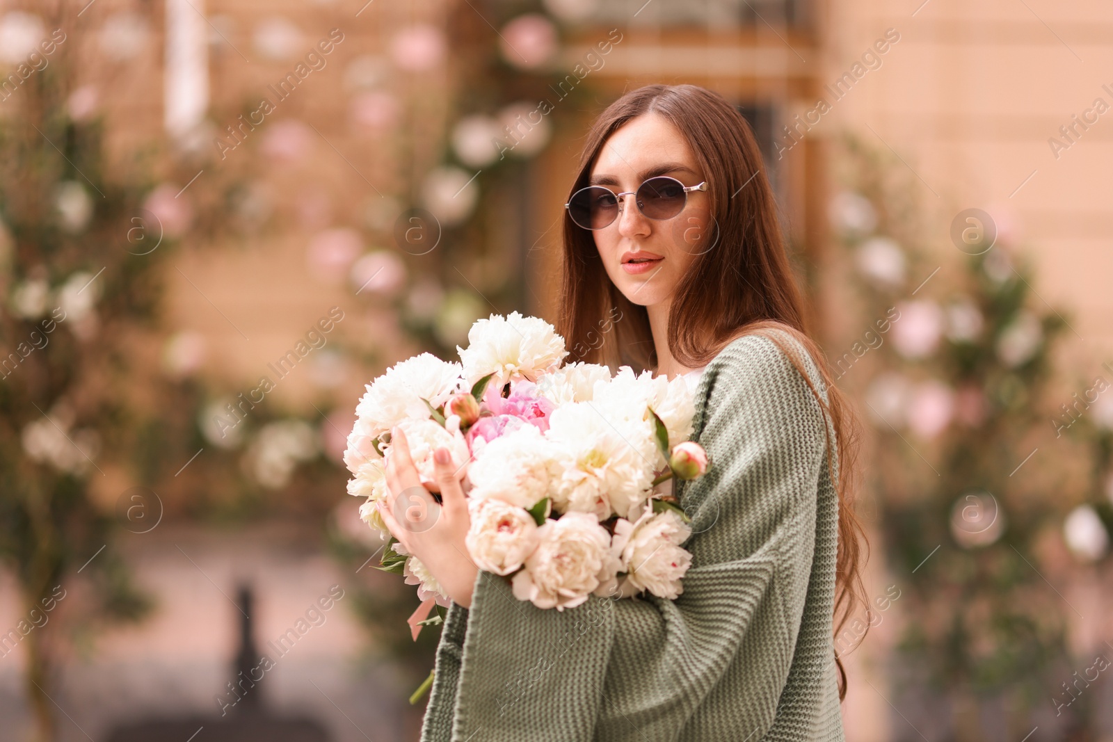 Charming woman with bouquet of beautiful peonies on city street. Space for text Photo of Charming woman with bouquet of beautiful peonies on city street. Space for text