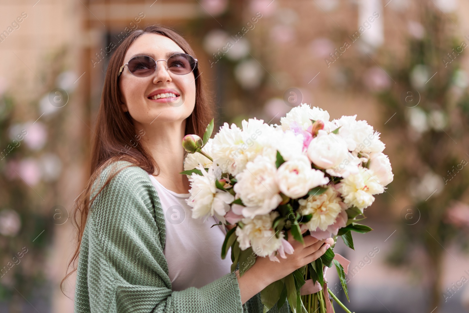 Charming woman with bouquet of beautiful peonies on city street Photo of Charming woman with bouquet of beautiful peonies on city street