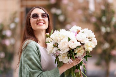 Photo of Charming woman with bouquet of beautiful peonies on city street