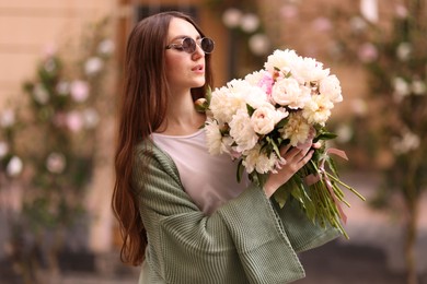 Photo of Charming woman with bouquet of beautiful peonies on city street