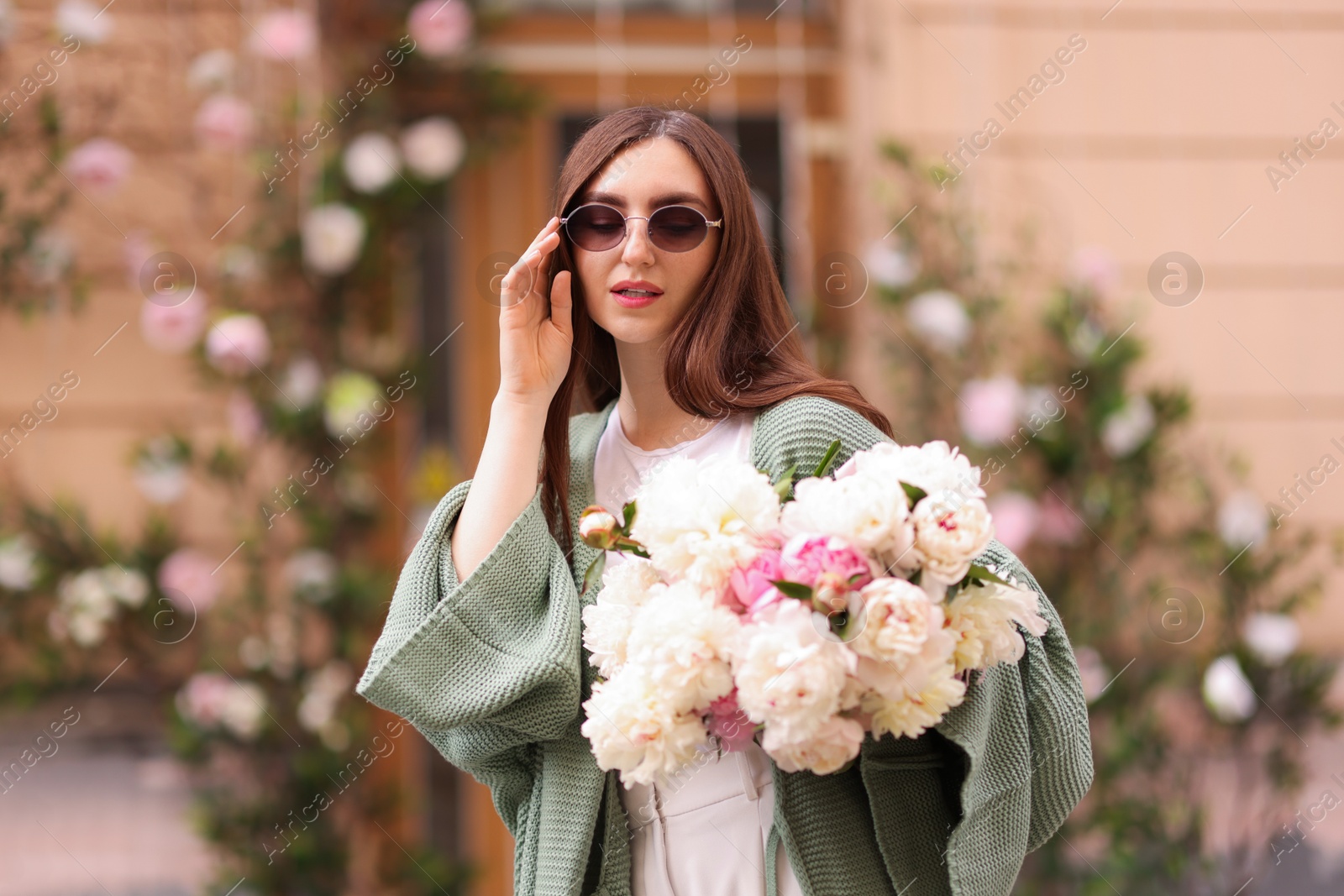 Charming woman with bouquet of beautiful peonies on city street Photo of Charming woman with bouquet of beautiful peonies on city street