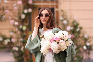 Photo of Charming woman with bouquet of beautiful peonies on city street