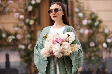 Photo of Charming woman with bouquet of beautiful peonies on city street