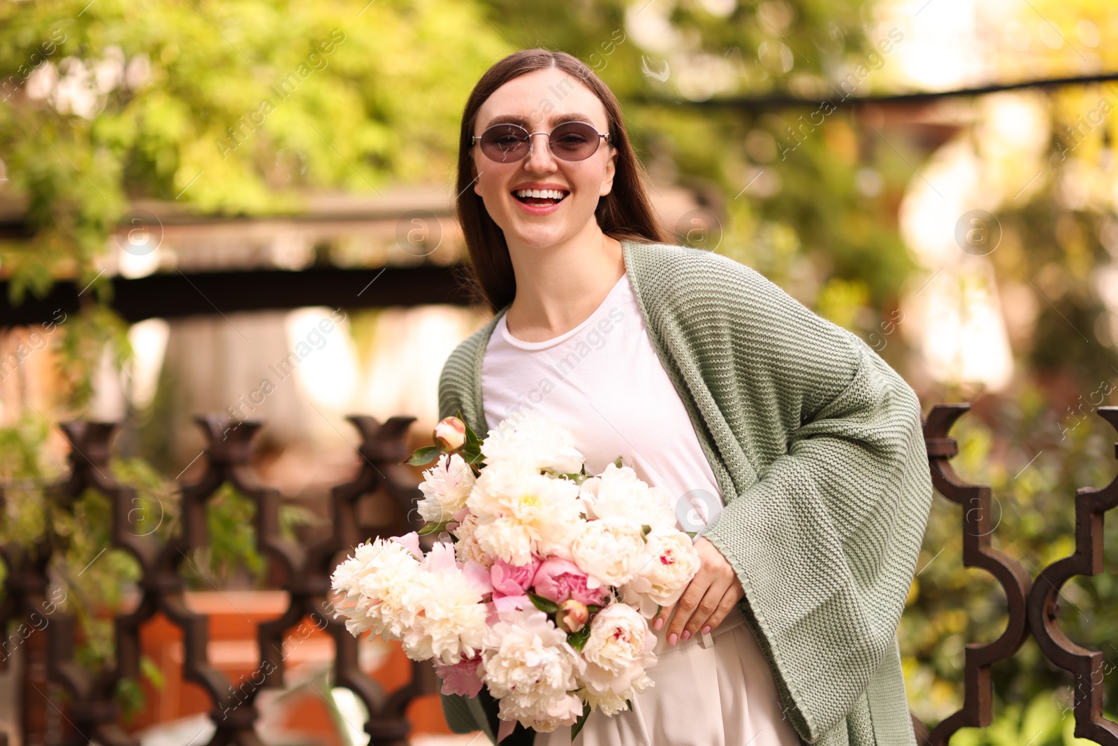 Charming woman with bouquet of beautiful peonies on city street Photo of Charming woman with bouquet of beautiful peonies on city street