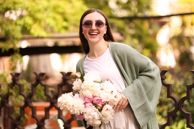 Photo of Charming woman with bouquet of beautiful peonies on city street