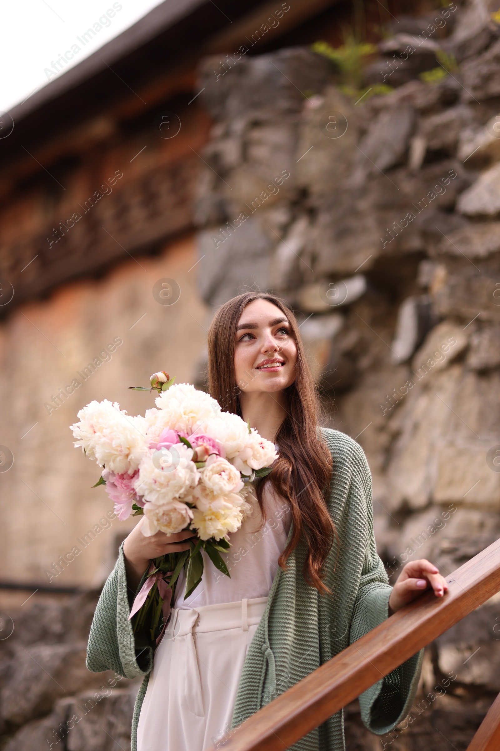 Charming woman with bouquet of beautiful peonies on city street Photo of Charming woman with bouquet of beautiful peonies on city street