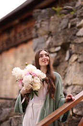 Photo of Charming woman with bouquet of beautiful peonies on city street