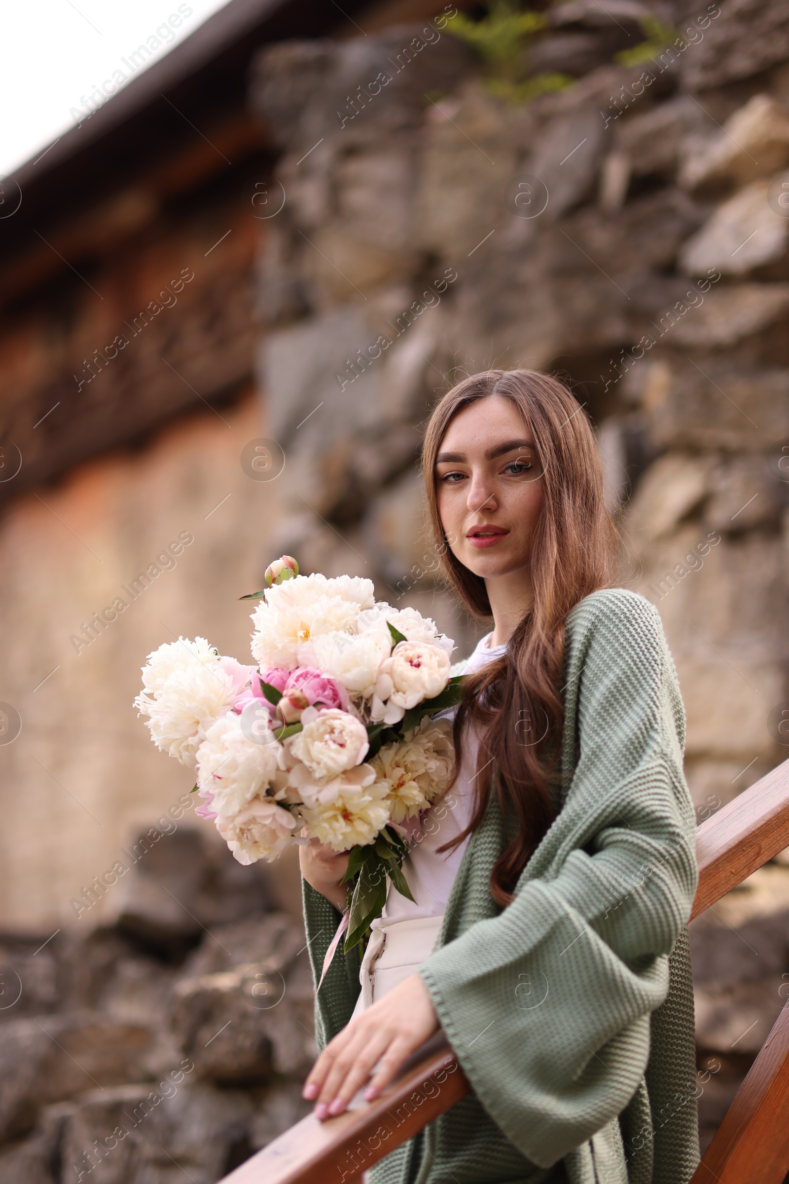Charming woman with bouquet of beautiful peonies on city street Photo of Charming woman with bouquet of beautiful peonies on city street