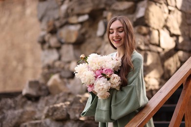 Photo of Charming woman with bouquet of beautiful peonies on city street. Space for text