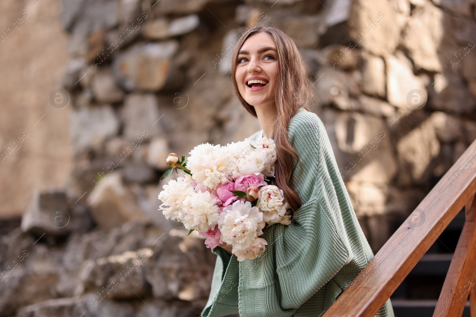 Charming woman with bouquet of beautiful peonies on city street. Space for text Photo of Charming woman with bouquet of beautiful peonies on city street. Space for text