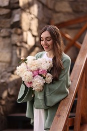 Photo of Charming woman with bouquet of beautiful peonies on city street