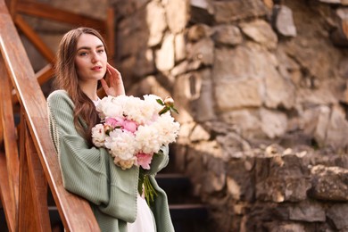 Photo of Charming woman with bouquet of beautiful peonies on city street. Space for text