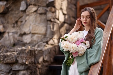 Photo of Charming woman with bouquet of beautiful peonies on city street. Space for text