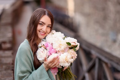 Photo of Charming woman with bouquet of beautiful peonies on city street. Space for text