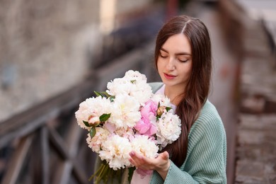 Photo of Charming woman with bouquet of beautiful peonies on city street. Space for text