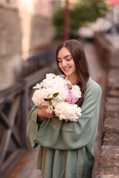 Photo of Charming woman with bouquet of beautiful peonies on city street