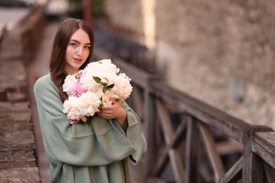 Photo of Charming woman with bouquet of beautiful peonies on city street. Space for text