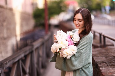 Photo of Charming woman with bouquet of beautiful peonies on city street. Space for text