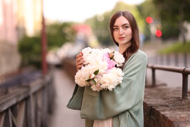 Photo of Charming woman with bouquet of beautiful peonies on city street. Space for text