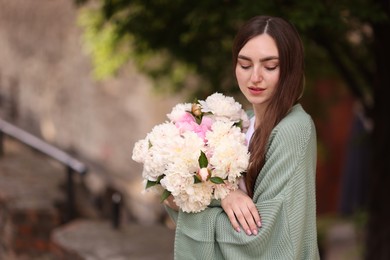 Photo of Charming woman with bouquet of beautiful peonies on city street. Space for text