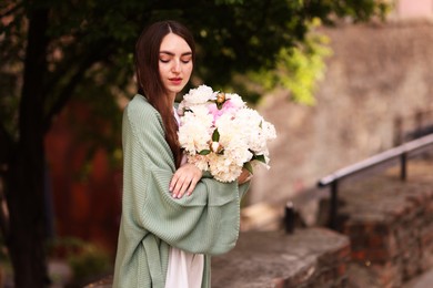 Photo of Charming woman with bouquet of beautiful peonies on city street. Space for text