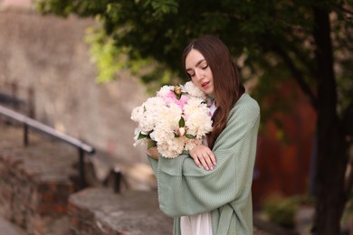 Photo of Charming woman with bouquet of beautiful peonies on city street. Space for text