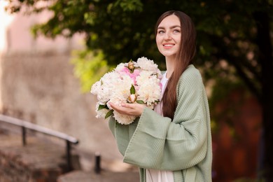 Photo of Charming woman with bouquet of beautiful peonies on city street