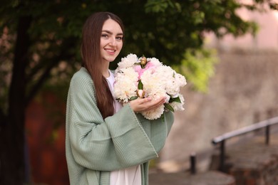 Photo of Charming woman with bouquet of beautiful peonies on city street