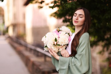 Photo of Charming woman with bouquet of beautiful peonies on city street. Space for text