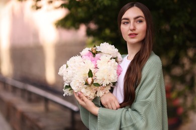 Photo of Charming woman with bouquet of beautiful peonies on city street