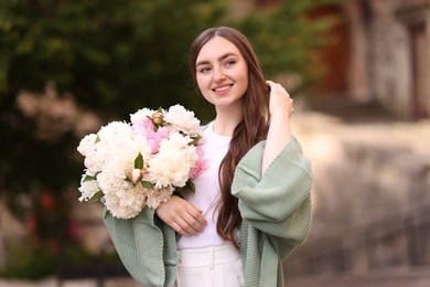 Photo of Charming woman with bouquet of beautiful peonies on city street