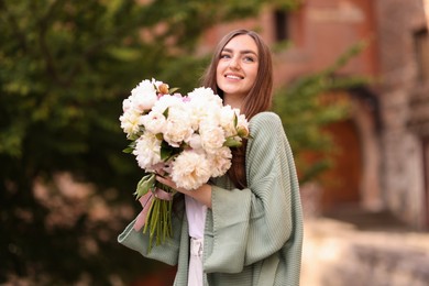 Photo of Charming woman with bouquet of beautiful peonies on city street