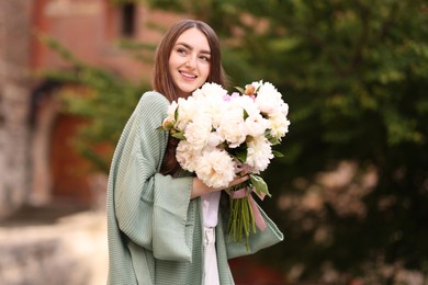 Photo of Charming woman with bouquet of beautiful peonies on city street
