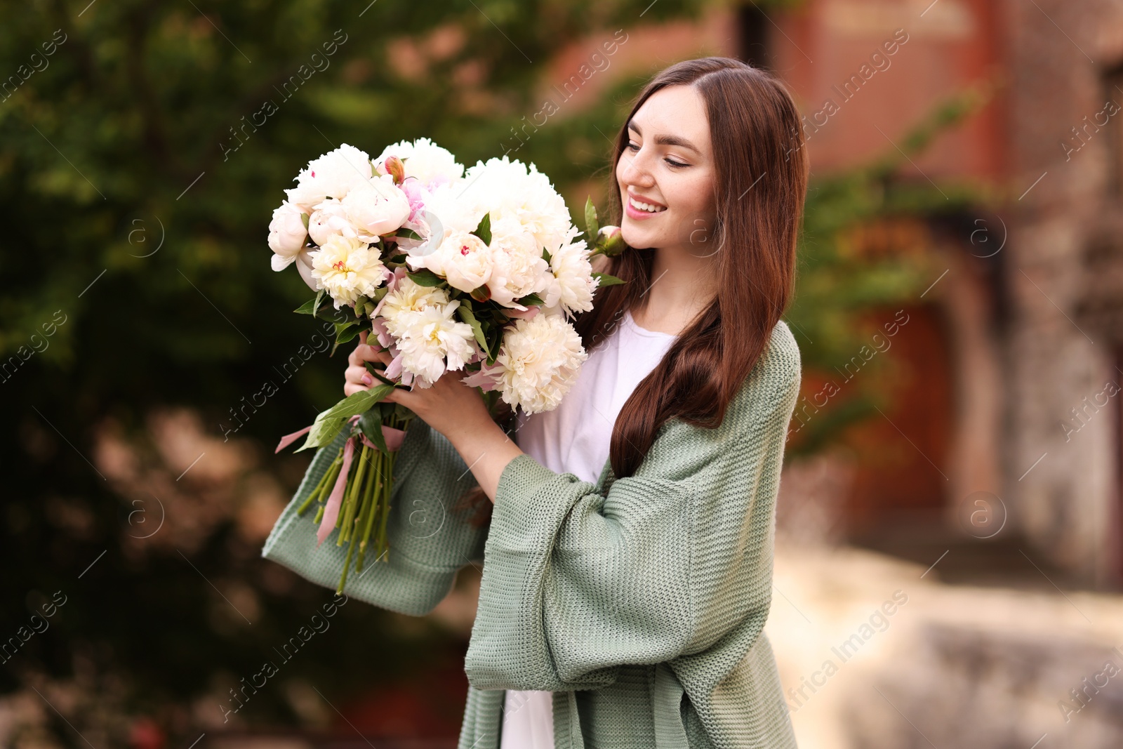 Charming woman with bouquet of beautiful peonies on city street Photo of Charming woman with bouquet of beautiful peonies on city street