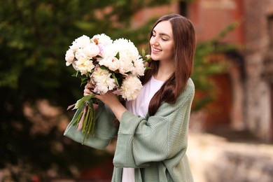 Photo of Charming woman with bouquet of beautiful peonies on city street