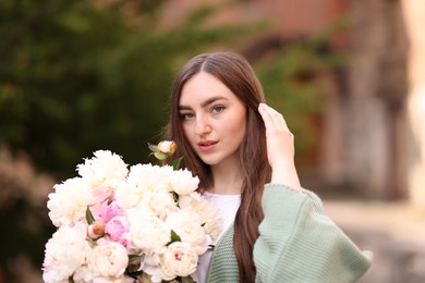 Photo of Charming woman with bouquet of beautiful peonies on city street