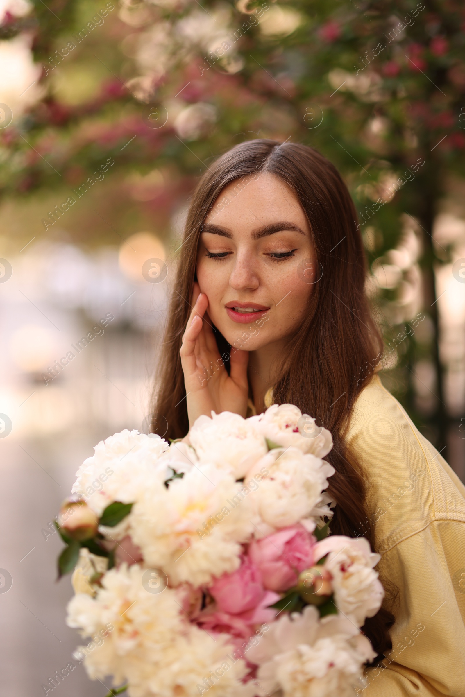 Woman with bouquet of beautiful peonies on city street Photo of Woman with bouquet of beautiful peonies on city street