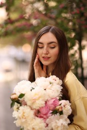Photo of Woman with bouquet of beautiful peonies on city street