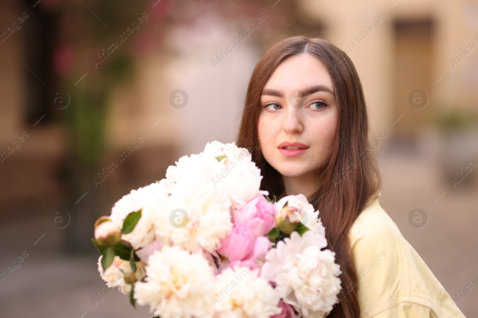 Woman with bouquet of beautiful peonies on city street Photo of Woman with bouquet of beautiful peonies on city street