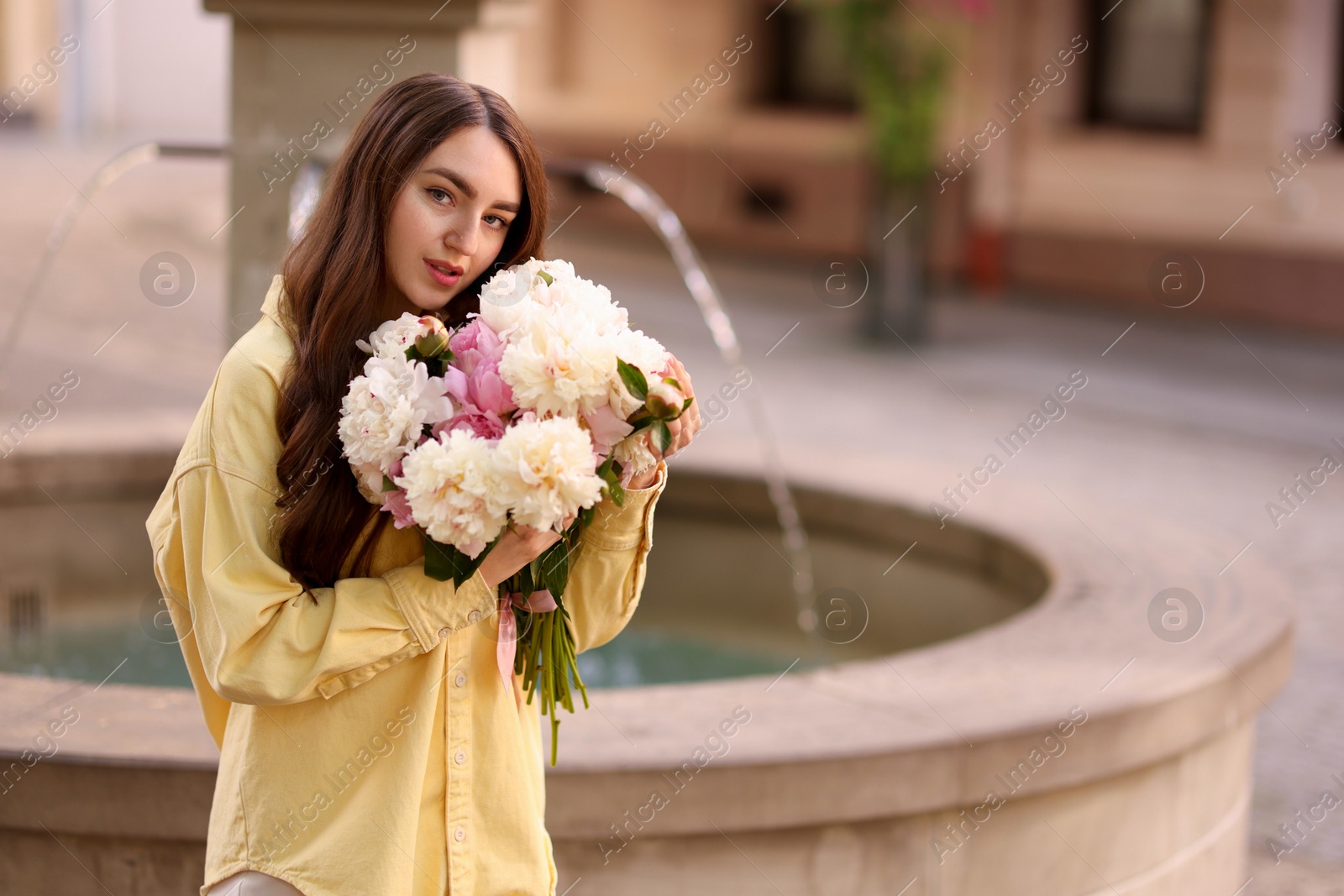 Woman with bouquet of beautiful peonies on city street. Space for text Photo of Woman with bouquet of beautiful peonies on city street. Space for text