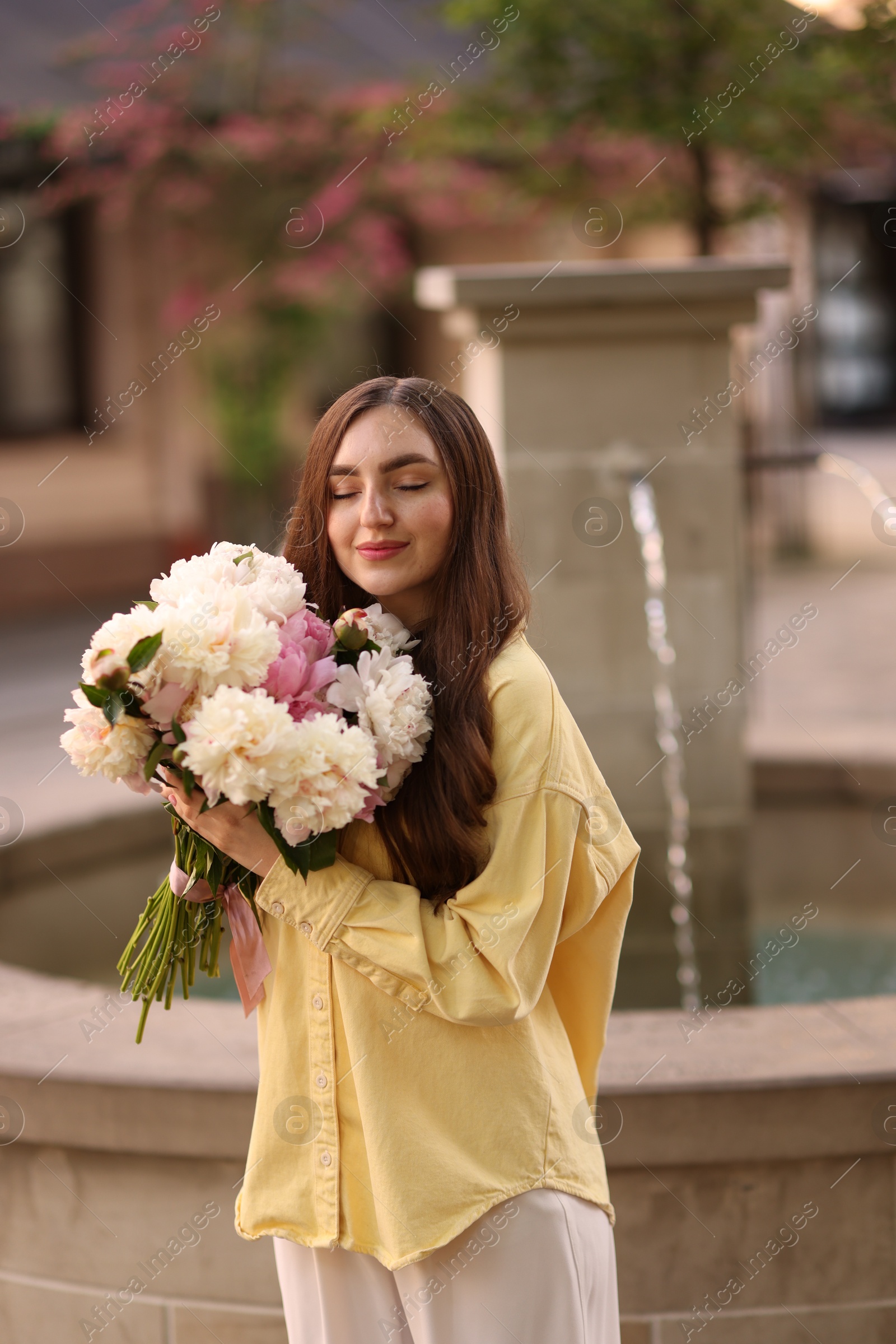 Photo of Woman with bouquet of beautiful peonies on city street