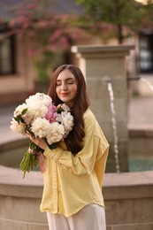 Photo of Woman with bouquet of beautiful peonies on city street