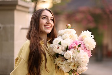 Photo of Woman with bouquet of beautiful peonies on city street