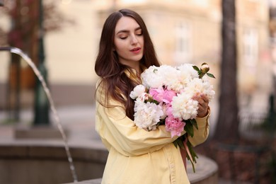 Photo of Woman with bouquet of beautiful peonies on city street