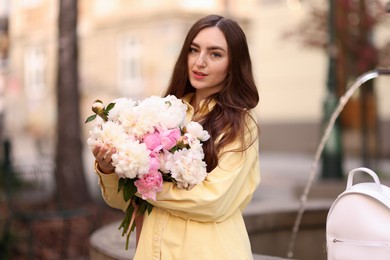 Photo of Woman with bouquet of beautiful peonies on city street