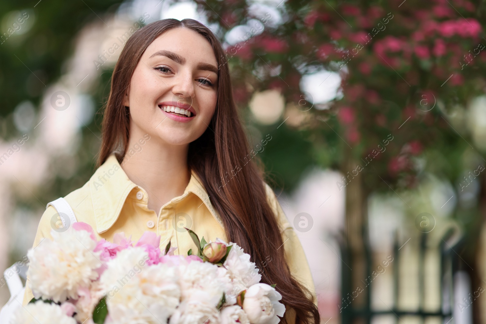 Woman with bouquet of beautiful peonies on city street. Space for text Photo of Woman with bouquet of beautiful peonies on city street. Space for text