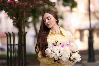 Photo of Woman with bouquet of beautiful peonies on city street
