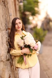 Photo of Woman with bouquet of beautiful peonies on city street